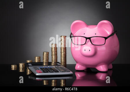 Close-up of Piggy Bank, calculatrice et pièces empilées Banque D'Images