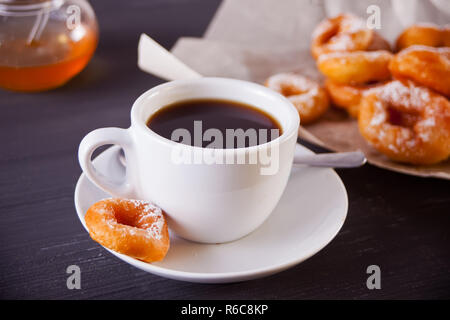 Petits beignets frais avec une tasse de café sur la table de nuit en bois Banque D'Images