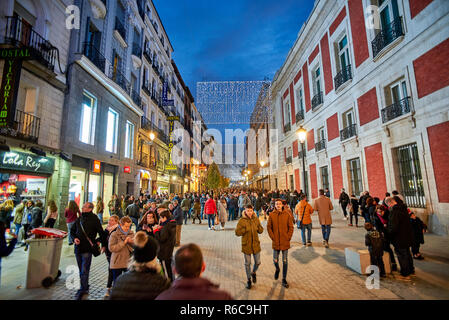 Les gens qui marchent sur la Calle de Carretas à la tombée de la rue éclairée par des lumières de Noël. Vue de la place Puerta del Sol. Banque D'Images