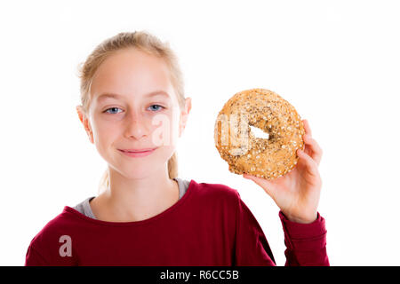 Jeune fille blonde à la recherche à travers un gros bagel Banque D'Images