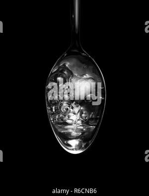 Vue en noir et blanc de l'image ci-dessus du liquide bouillonnant dans une cuillère Banque D'Images