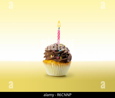 Birthday cupcake avec du glaçage et bougie allumée Banque D'Images