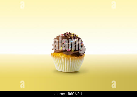 Cupcake chocolat avec glaçage sur une surface jaune Banque D'Images