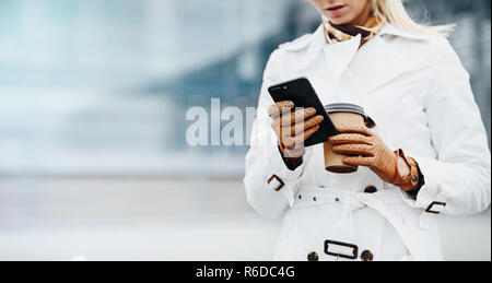 Belle femme avec une tasse à café près de l'immeuble de bureaux. Banque D'Images