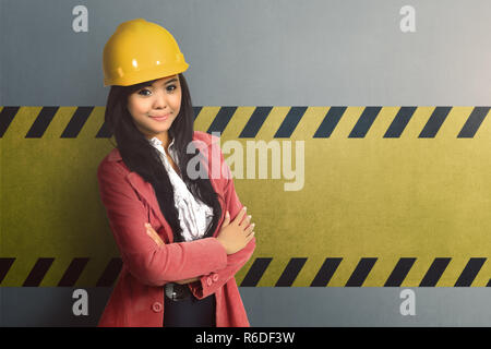 Smiling worker femme avec casque jaune et traversé part Banque D'Images