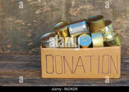 Donation box avec différents aliments en conserve sur le vieux fond de bois. Banque D'Images