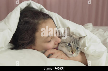 Happy teen girl baisers et des pourparlers avec Thai cat in bed Banque D'Images