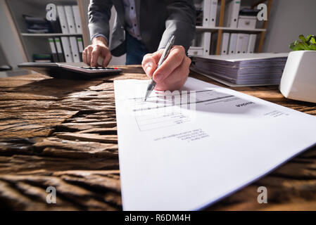 À l'aide d'affaires tout en signant le document de la calculatrice Banque D'Images