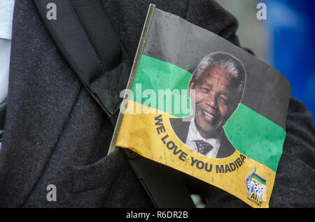Un drapeau portant la photo de Nelson Mandela, affectueusement appelé Madiba, dépasse d'une poche de veste, l'endeuillé à un service commémoratif des pluies pour l'ancien président sud-africain au FNB Stadium, à Soweto, le mardi 10 décembre 2013. Mandela est mort le 5 décembre 2013. Madiba est terme de respect dérivé de Mandela's nom de clan Xhosa. PHOTO : EVA-LOTTA JANSSON Banque D'Images
