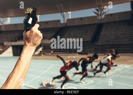 Close up of hand le tir d'un pistolet de démarreur pour démarrer la course à pied. Les athlètes de partir pour une course sur une piste de course. Banque D'Images