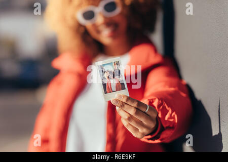 Blur shot d'une femme en vacances, montrant une photo Polaroid. Close up d'un polaroid photo dans la main d'un female traveller standin Banque D'Images