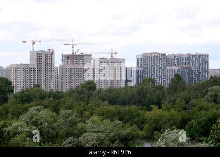 La construction de la ville. Paysage avec grues et nouveau bloc d'appartements de construction au nouveau quartier écologique vert ciel avec nuages blancs en journée d'été Banque D'Images