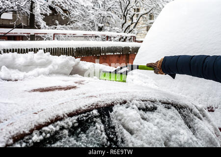 Jeune homme nettoyant sa voiture de la neige à l'aide d'un pinceau. Enlever la neige de l'automobile Banque D'Images