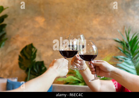 Groupe d'amis célébration cheering with red wine in restaurant. Banque D'Images