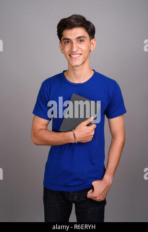 Beau jeune adolescent Persique student holding book Banque D'Images