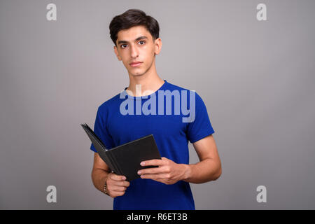 Beau jeune adolescent Persique student holding book Banque D'Images