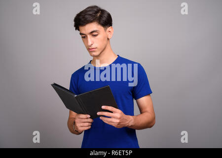 Beau jeune adolescent Persique student holding book Banque D'Images