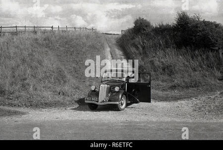 1950s, une voiture Ford Anglia de l'époque garée sur une layette en gravier au parc national d'Exmoor, Devon, Angleterre, Royaume-Uni. Banque D'Images