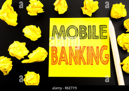 Texte manuscrit montrant Mobile Banking. L'écriture du concept d'entreprise pour les services bancaires par Internet e-bank écrit le post-it sur le fond noir. Papiers pliés sur l'arrière-plan jaune Banque D'Images