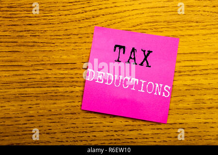 Texte d'annonce d'écriture montrant des déductions fiscales. Concept d'affaires pour financer l'impôt Déduction de l'argent entrant écrit sur sticky note papier vide, fond de bois avec copie espace, lunettes de soleil. Banque D'Images