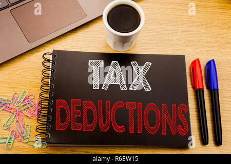 Texte d'annonce d'écriture montrant des déductions fiscales. Concept d'affaires pour financer l'impôt Déduction de l'argent entrant sur le portable écrit le livre sur fond de bois dans le bureau avec du café pour ordinateur portable Banque D'Images