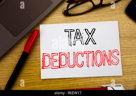 Texte d'annonce d'écriture montrant des déductions fiscales. Concept d'affaires pour financer l'impôt Déduction de l'argent entrant écrit sur papier, fond de bois dans Office avec copie espace, feutre et verres Banque D'Images
