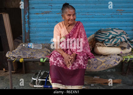 Une femme indienne, un migrant d'Inde du Nord, faisant de sa maison sur le trottoir par un marché aux poissons à Mumbai, Inde Banque D'Images