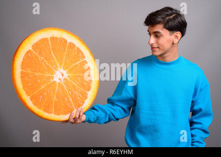 Young woman holding persan grande tranche de fruits orange Banque D'Images