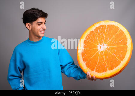 Young woman holding persan grande tranche de fruits orange Banque D'Images