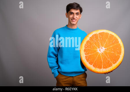 Young woman holding persan grande tranche de fruits orange Banque D'Images