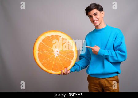 Young woman holding persan grande tranche de fruits orange Banque D'Images