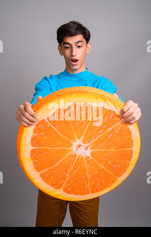 Young woman holding persan grande tranche de fruits orange Banque D'Images