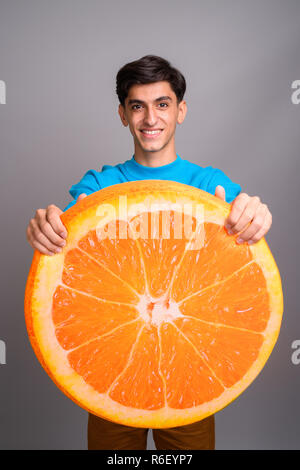 Young woman holding persan grande tranche de fruits orange Banque D'Images