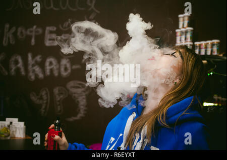 Jeune femme, le vendeur à vape shop shop, fumer la cigarette électronique, seine et libère un nuage de vapeur Banque D'Images