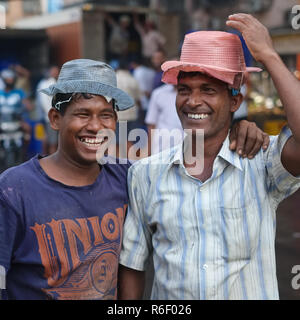 Deux porteurs souriants et souriants dans un marché aux poissons près de Crawford Market à Mumbai, en Inde, avec des chapeaux en plastique bon marché Banque D'Images