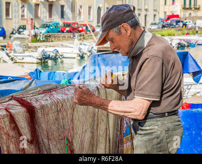 Vieux Pêcheur réparant le filet pour la pêche sur une zone que beaucoup appellent Piccola Venezia ou la petite Venise, ville de Livourne en Toscane, Italie Banque D'Images