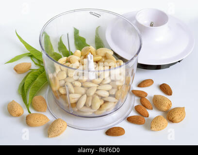 Amandes mondées dans un blender avec les écrous. Sur fond blanc. Banque D'Images