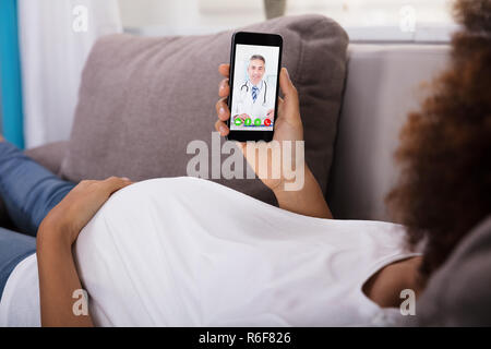 Femme enceinte la visioconférence avec médecin sur smartphone Banque D'Images