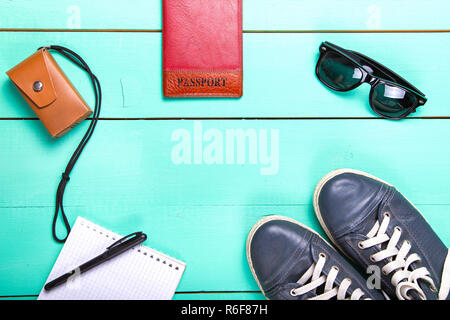 Set de voyage, Passeport, e-book, chaussures, lunettes de soleil, appareil photo. on a wooden surface turquoise, une vue de dessus Banque D'Images