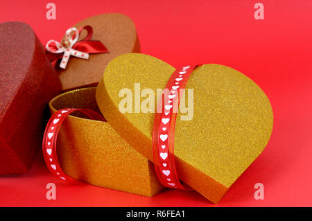 Cadeaux saint valentin rouge et or sur un fond de papier rouge. Banque D'Images