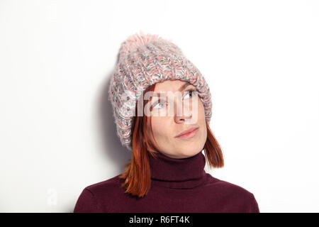 Portrait isolé de belle jeune fille rousse aux yeux verts à sideaways en violet et rose pull tricoté chapeau avec pompon habillé sideway Banque D'Images