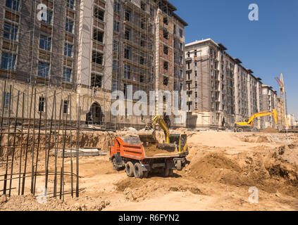 Sur le site de construction, les charges de la pelle la terre dans le dump truck Banque D'Images