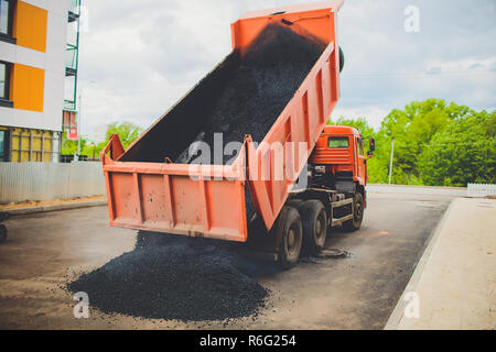 Les déchargements de camions dans l'épandeur d'asphalte frais sur grande route dans la ville Banque D'Images