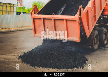 Les déchargements de camions dans l'épandeur d'asphalte frais sur grande route dans la ville Banque D'Images