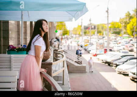 Cute asian young woman in cafe d'été à l'extérieur. fille en T-shirt blanc, avec de longs cheveux dans la lumière simple intérieur cosy restaurant de style urbain Banque D'Images