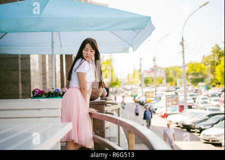 Cute asian young woman in cafe d'été à l'extérieur. fille en T-shirt blanc, avec de longs cheveux dans la lumière simple intérieur cosy restaurant de style urbain Banque D'Images