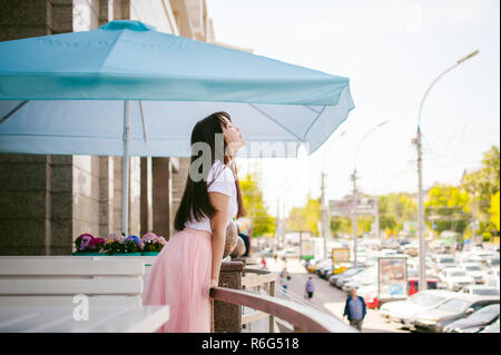 Cute asian young woman in cafe d'été à l'extérieur. fille en T-shirt blanc, avec de longs cheveux dans la lumière simple intérieur cosy restaurant de style urbain Banque D'Images