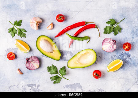Ingrédients pour le guacamole : avocat, citron vert, tomate, oignon et épices, vue du dessus. Banque D'Images