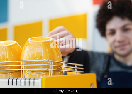Friendly barista vers de tasse à café et debout derrière comptoir bar. Banque D'Images