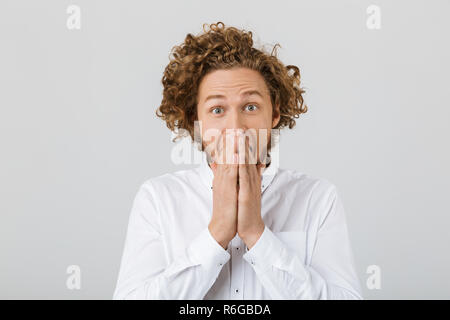 Portrait d'un jeune homme surpris avec des cheveux bouclés isolated over white background, couvrir la bouche avec armoiries Banque D'Images